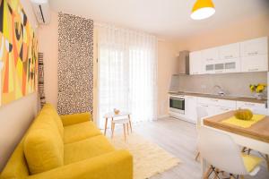 a living room with a yellow couch and a kitchen at Lovely apartment Lungomare in Vlorë