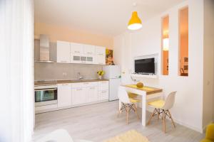 a kitchen with white cabinets and a table and chairs at Lovely apartment Lungomare in Vlorë