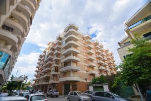 a tall building with cars parked in front of it at Lovely apartment Lungomare in Vlorë