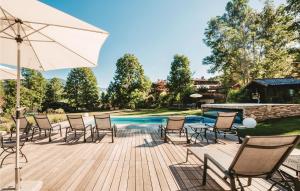 a deck with chairs and an umbrella next to a pool at Amazing Apartment In Wagrain With 1 Bedrooms, Wifi And Outdoor Swimming Pool in Wagrain