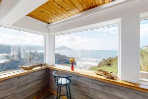 a room with windows with a chair and a view of the ocean at Seaside Serene in Port Orford