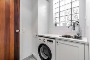 een witte keuken met een wastafel en een wasmachine bij Sails Five Inverloch in Inverloch