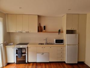 uma cozinha com armários brancos, um lavatório e um frigorífico em Beatons Beach Front Studio Inverloch em Inverloch