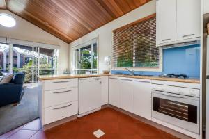 a kitchen with white cabinets and a wooden ceiling at Beachy Haven at Sails close to the Beach in Inverloch