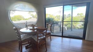 a dining room with a table and chairs and a large window at Romantic Retreat Inverloch in Inverloch