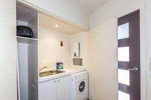 uma pequena cozinha com um lavatório e uma máquina de lavar roupa em Romantic Retreat Inverloch em Inverloch