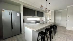 a kitchen with a refrigerator and a counter with stools at Somerset on Murray in Inverloch