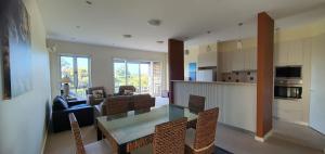 a kitchen and living room with a glass table and chairs at Coastal Soul Villa at Broadbeach in Inverloch