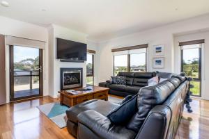 a living room with a leather couch and a fireplace at Surfside Lakeviews Free Wifi in Inverloch
