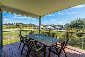 einen Holztisch und Stühle auf einer Terrasse mit Aussicht in der Unterkunft Surfside Lakeviews Free Wifi in Inverloch