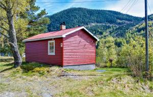a small red house in a field with a tree at Heggebu in Vråliosen