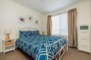 a bedroom with a blue and white bed and a window at EAGLES NEST VIEWS ON TAMARA in Inverloch