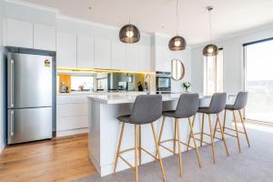 a kitchen with a bar with chairs and a refrigerator at Views Forever Inverloch in Inverloch
