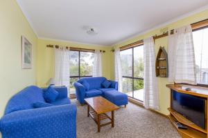 a living room with two blue chairs and a tv at Holiday on Nautilus Inverloch in Inverloch