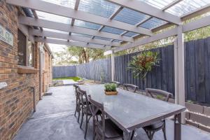 a patio with a table and chairs and a pergola at Perfect on Pymble Ave in Inverloch