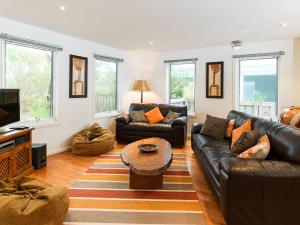 un soggiorno con divani in pelle e TV di Evergreen Beach House a Inverloch