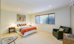a bedroom with a bed and a chair and a window at Surfside Getaway in Picturesque Inverloch in Inverloch