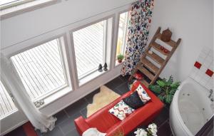 1 Bedroom Awesome Home In Vimmerby في فيمربي: غرفة معيشة بها نافذتين وكرسي احمر