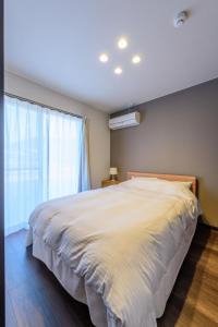 ein Schlafzimmer mit einem großen weißen Bett und einem Fenster in der Unterkunft Rakuten STAY HOUSE x WILL STYLE Sasebo 104 in Sasebo