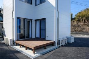 Rakuten STAY HOUSE x WILL STYLE Sasebo 103 في ساسيبو: منزل على جانبه مقعد خشبي