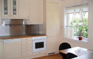 cocina con armarios blancos, mesa y ventana en Amazing Home In Bygland With House Sea View, en Bygland