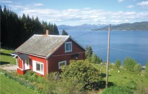 a red house on a hill next to a body of water at Lovely Home In Vågstranda in Hjelvik