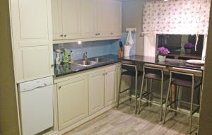 a kitchen with white cabinets and a sink and bar stools at Lovely Home In Vågstranda in Hjelvik +18 photos