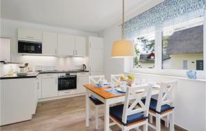 eine weiße Küche mit einem Holztisch und Stühlen in der Unterkunft Reetdachhaus 5 Auf Usedom in Kutzow