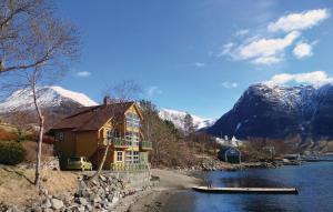 a house on the side of a river with snowy mountains at Amazing Apartment In Rosendal With Sauna in Rosendal