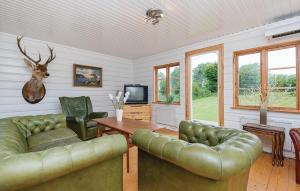 sala de estar con mesa y muebles de cuero verde en Beautiful Home In Holmsj With Lake View, en Holmsjö