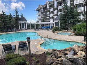 a swimming pool with two chairs and a building at Allegheny Spring 239 KING, bed/Ski-In, Out/Pool & Hot Tub in Snowshoe