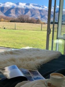 einen Blick auf ein Feld aus dem Fenster mit einer Tasse Kaffee in der Unterkunft Fox Cottage in Ashwick Flat