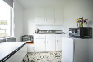 a kitchen with white cabinets and a sink and a microwave at Ranfurly Motels in Ranfurly