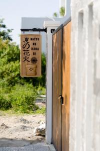 a wooden door with a sign on it next to a building at Natsu No Hanabi Villa & Apartment in Da Nang