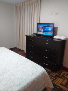 リマにあるApart Hotel Don Ernestoのベッドルーム(ベッド1台、ドレッサー内のテレビ付)