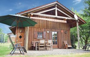 eine kleine Holzhütte mit Stühlen und einem Sonnenschirm in der Unterkunft Awesome Home In Waldmnchen With 3 Bedrooms And Wifi in Kleinschönthal
