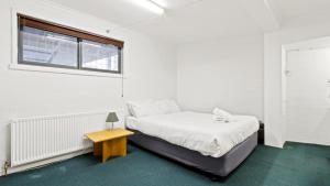 a white bedroom with a bed and a table at Alpine Heights 11B in Mount Hotham +3 photos