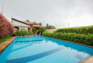 una gran piscina azul frente a una casa en Porto das Dunas Casa Temporada Estilo e Conforto, en Fortaleza