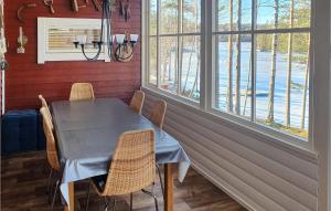 a dining room with a table and chairs and windows at Beautiful Home In Svanskog With 2 Bedrooms And Sauna in Slirud