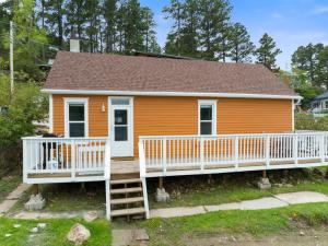 una pequeña casa naranja con porche y escaleras en The Overlook Nook en Lead