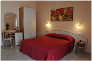 1 dormitorio con cama roja y escritorio en Hotel Vittoria, en Benevento
