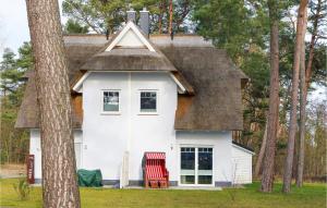 a house with a thatched roof and a red chair at Reetdachhaus 11 Auf Usedom in Kutzow