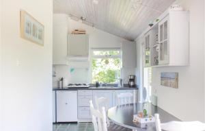a kitchen with white cabinets and a table and chairs at Awesome Home In Lauwersoog With Kitchen in Lauwersoog