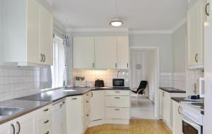 トメリラにあるAmazing Home In Tomelilla With 6 Bedrooms And Wifiの白いキッチン(白いキャビネット、シンク付)