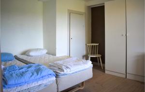 トメリラにあるGorgeous Home In Tomelilla With Wifiのベッド2台と椅子が備わる客室です。