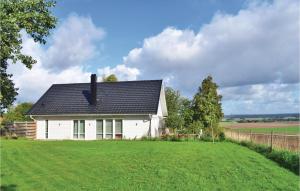 a white house with a black roof on a green field at Lovely Home In ngelholm With Outdoor Swimming Pool in Ängelholm