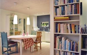 a dining room with a table and bookshelves filled with books at Lovely Home In ngelholm With Outdoor Swimming Pool in Ängelholm