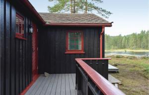 ein schwarzes Haus mit einem roten Fenster und einer Terrasse in der Unterkunft Lovely Home In Vegårshei With Sauna in Vegårshei