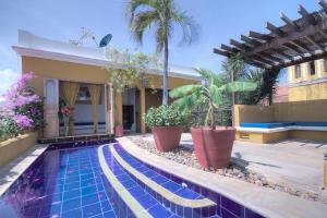 a swimming pool in front of a house with palm trees at Casa El Carretero Hotel Boutique in Cartagena de Indias