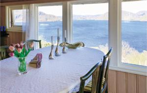 a table with a vase of flowers in a room with windows at Nice Home In Farsund With Wifi in Farsund